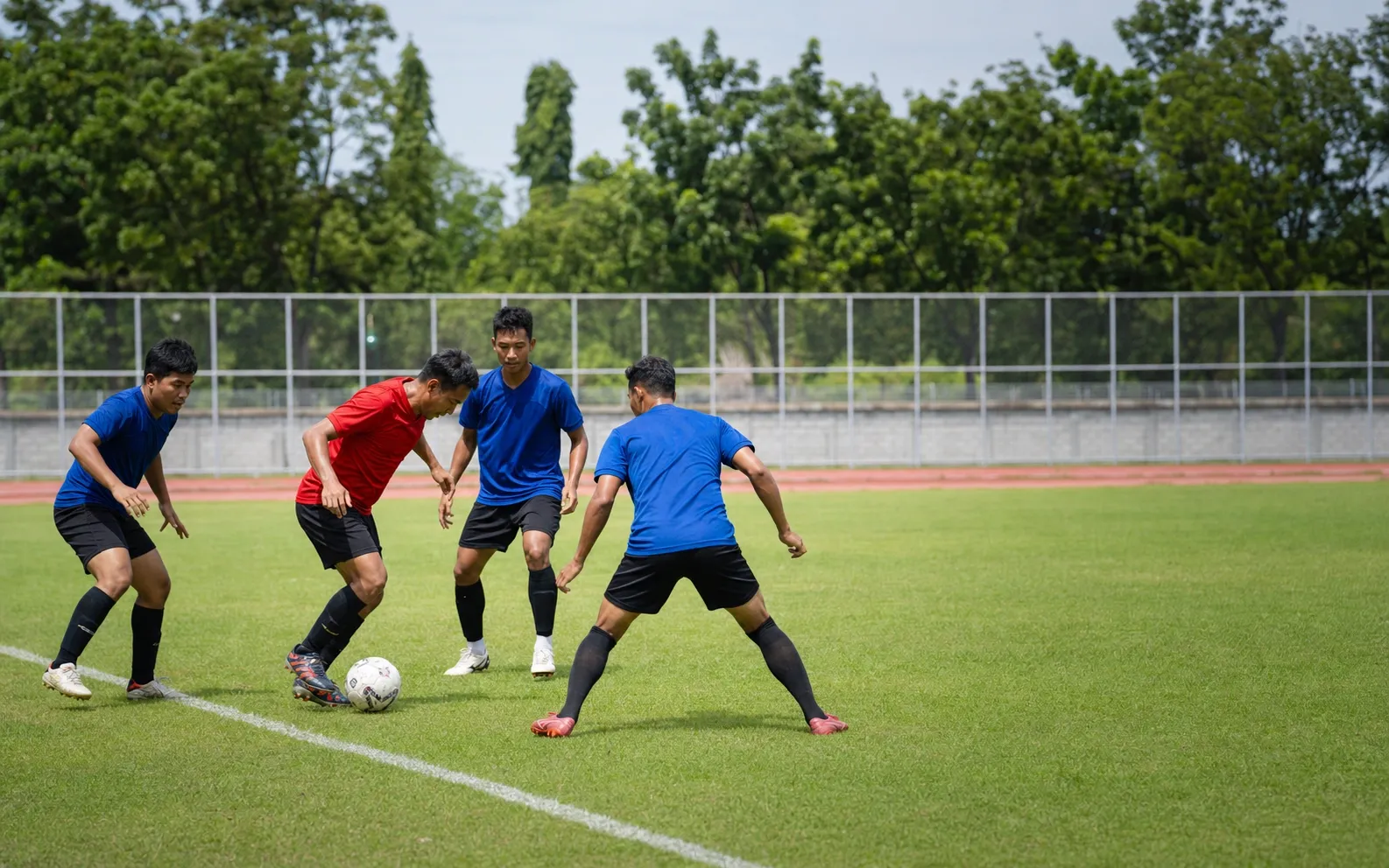 Tiga pemain menekan rekan setim dekat garis samping dalam latihan high press