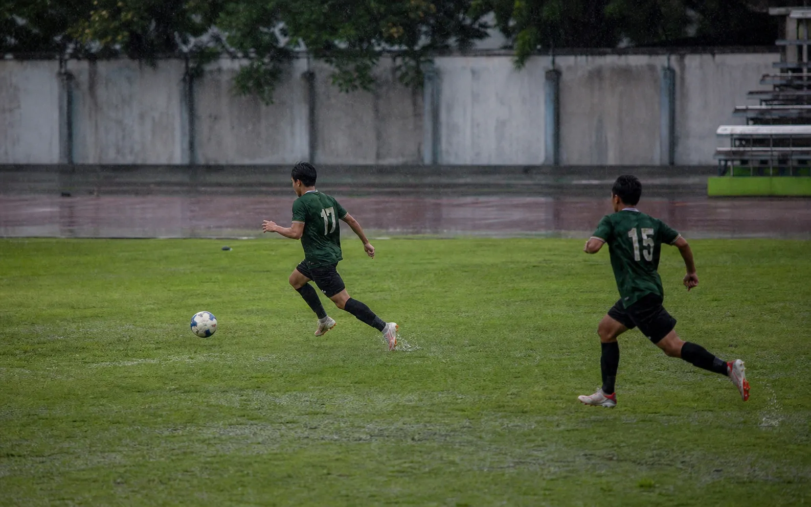 Dua pemain berlari ke ruang terbuka saat memulai serangan balik di lapangan basah