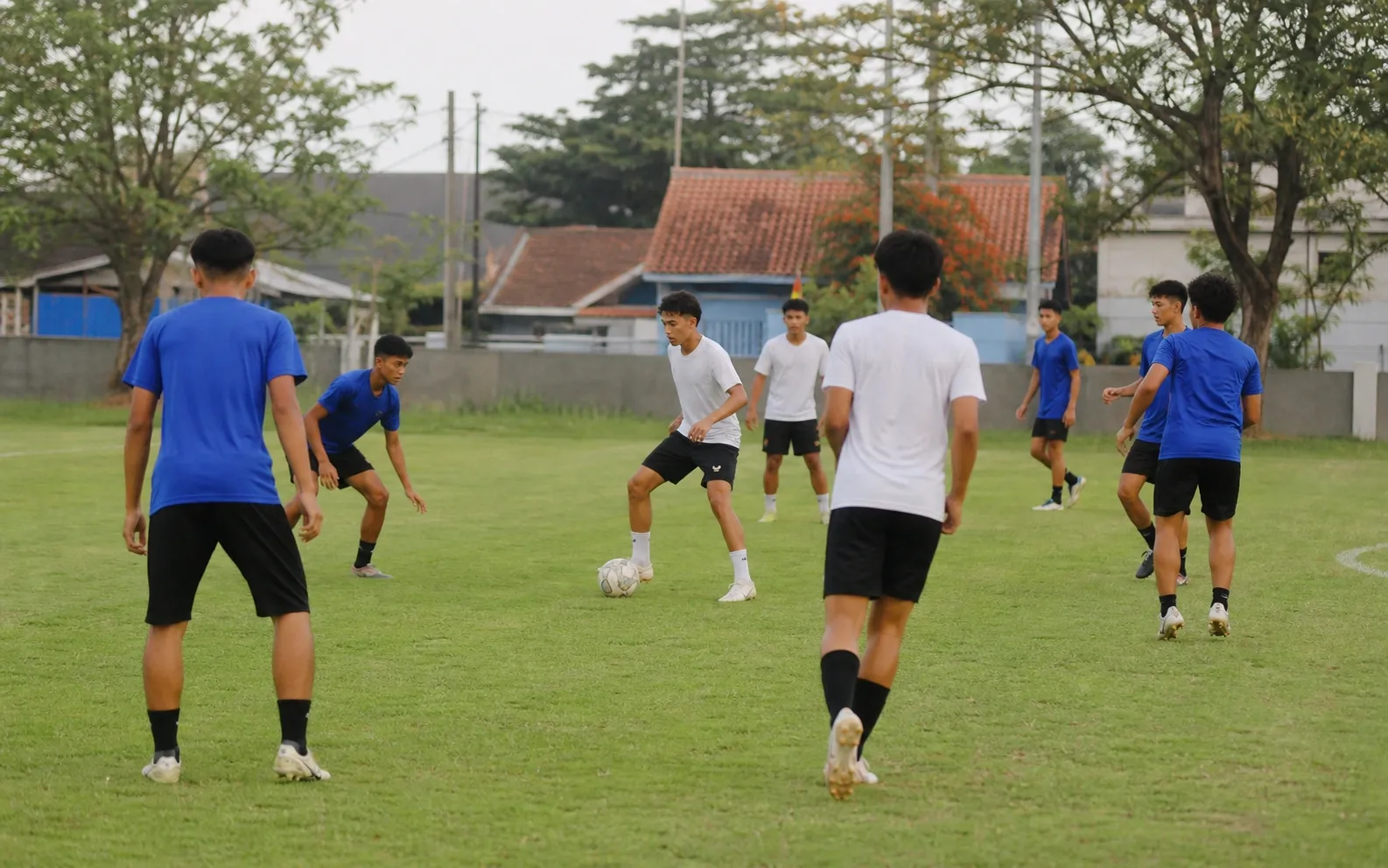 Tiga pemain menjalankan kombinasi umpan dan lari pemain ketiga di lapangan taman